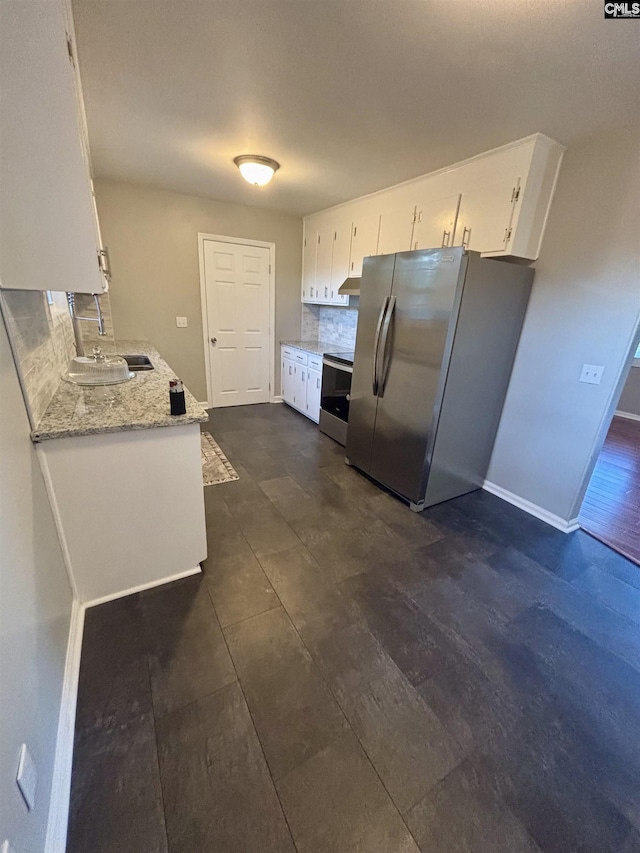 kitchen featuring light stone counters, stainless steel appliances, a sink, white cabinetry, and decorative backsplash