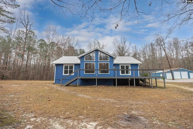 back of house featuring a garage, metal roof, stairway, and an outdoor structure