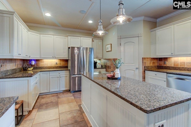 kitchen with decorative backsplash, appliances with stainless steel finishes, a center island, hanging light fixtures, and white cabinetry