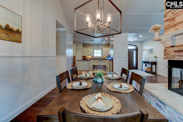 dining room with a chandelier, a wainscoted wall, a multi sided fireplace, and wood finished floors