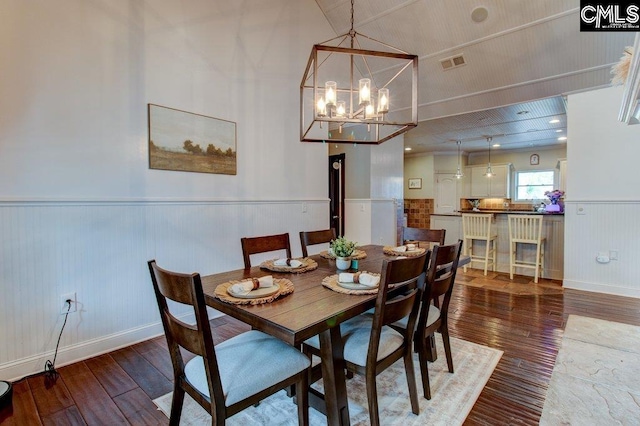 dining area with a notable chandelier, visible vents, dark wood-type flooring, and wainscoting