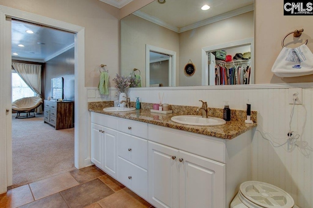 bathroom featuring double vanity, a spacious closet, ornamental molding, and a sink