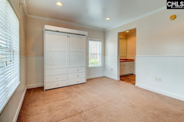 unfurnished bedroom featuring light carpet, recessed lighting, ornamental molding, and wainscoting