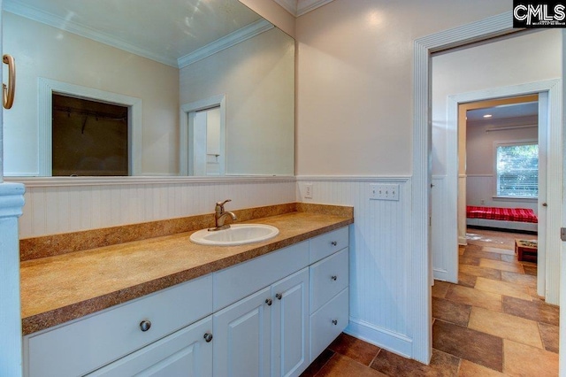 bathroom with wainscoting, crown molding, vanity, and ensuite bath