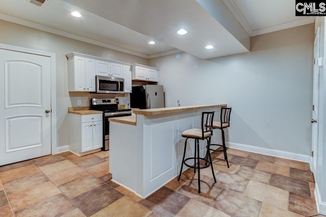 kitchen with stainless steel appliances, light countertops, white cabinetry, a peninsula, and a kitchen bar