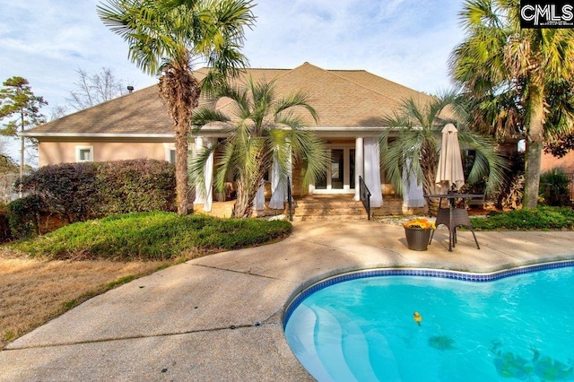 rear view of property featuring a patio area, an outdoor pool, and stucco siding