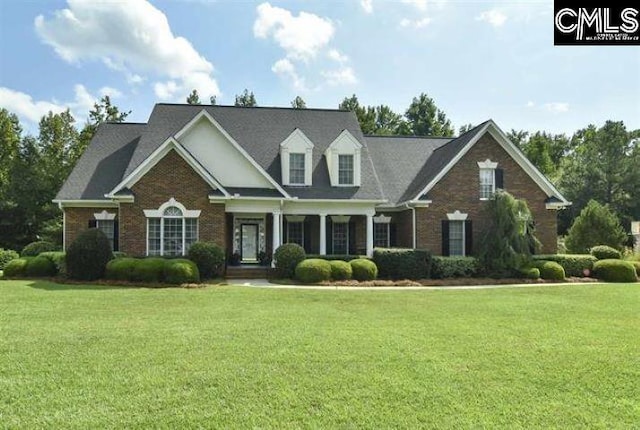 cape cod home featuring brick siding and a front yard