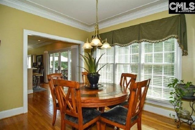 dining room with a notable chandelier, baseboards, crown molding, and wood finished floors