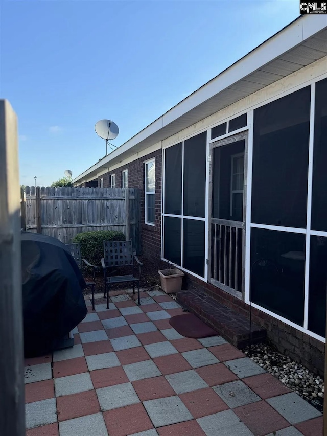 view of patio featuring a sunroom, fence, and grilling area