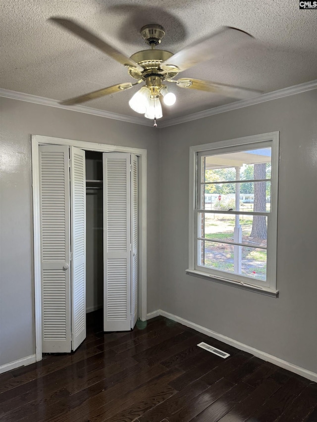 unfurnished bedroom with dark wood-type flooring, crown molding, and baseboards