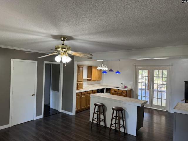 kitchen featuring light countertops, a breakfast bar, dark wood finished floors, and pendant lighting