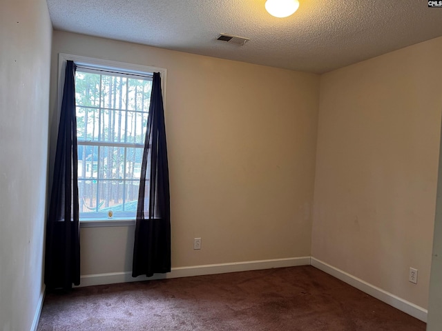 spare room with dark colored carpet, visible vents, plenty of natural light, and baseboards