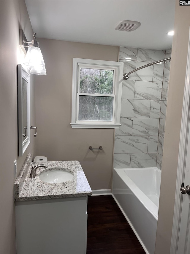 full bath with shower / bath combination, baseboards, visible vents, wood finished floors, and vanity