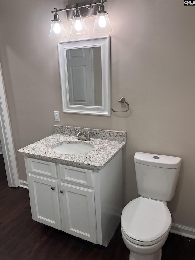 bathroom with toilet, baseboards, wood finished floors, and vanity