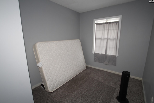 bedroom with dark colored carpet and baseboards