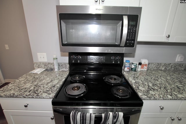 kitchen featuring light stone counters, white cabinets, black range with electric stovetop, and stainless steel microwave