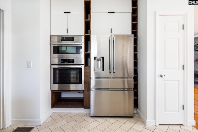 kitchen with white cabinets, baseboards, visible vents, and stainless steel appliances