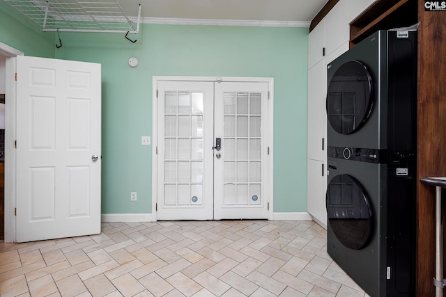 washroom featuring baseboards, french doors, cabinet space, and stacked washer / drying machine