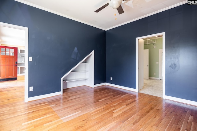 unfurnished room featuring crown molding, light wood-style flooring, baseboards, and ceiling fan