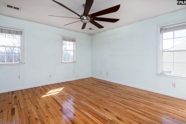 unfurnished room featuring light wood-style flooring, visible vents, and baseboards