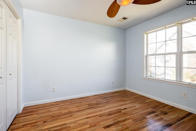 unfurnished bedroom with wood finished floors, a ceiling fan, visible vents, baseboards, and a closet