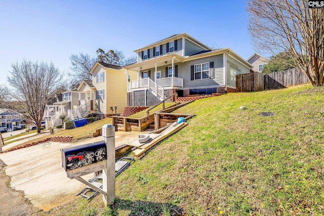 view of front facade with a residential view, covered porch, stairs, fence, and a front yard