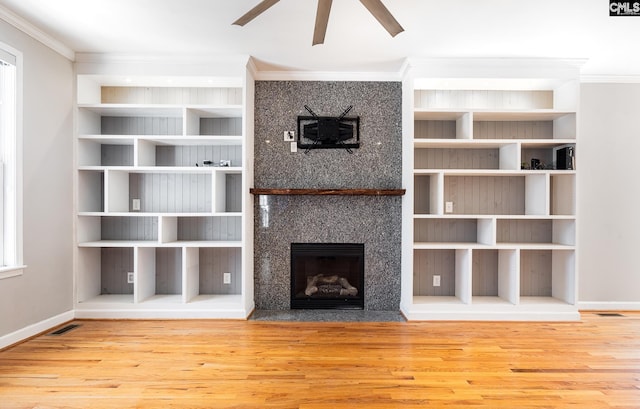 unfurnished living room featuring a fireplace with flush hearth, wood finished floors, visible vents, and crown molding