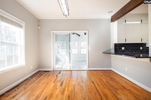 unfurnished dining area featuring light wood finished floors, baseboards, and ornamental molding