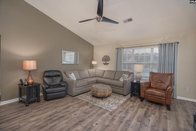 living area with lofted ceiling, visible vents, baseboards, and wood finished floors