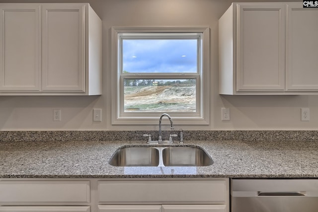 kitchen featuring dishwasher, a sink, white cabinetry, and light stone countertops