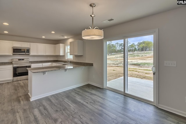 kitchen with white cabinets, decorative light fixtures, a peninsula, stainless steel appliances, and a sink