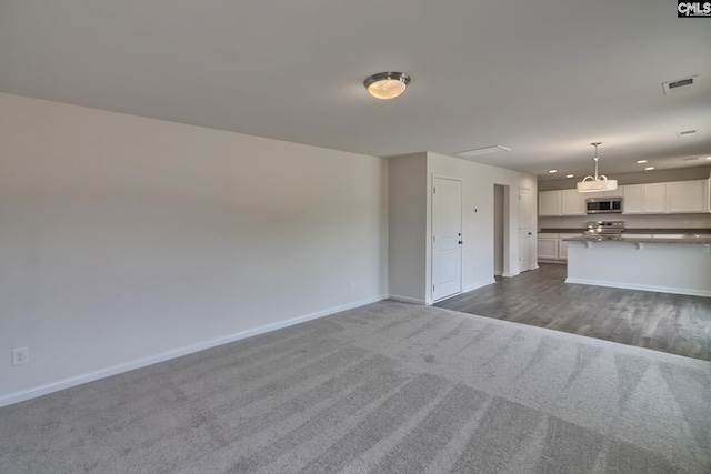 unfurnished living room featuring carpet flooring, visible vents, and baseboards