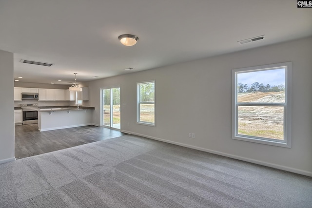 unfurnished living room featuring carpet floors, baseboards, visible vents, and recessed lighting