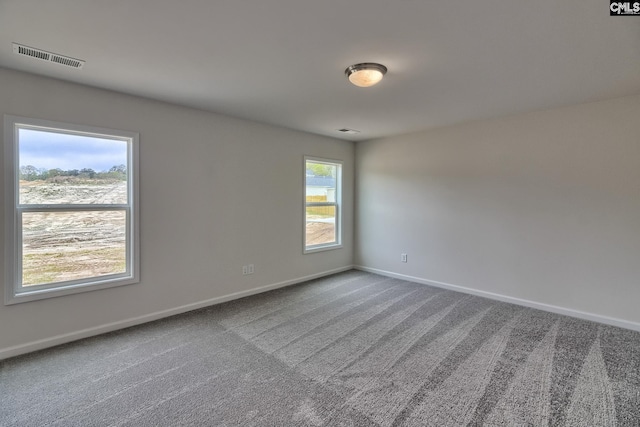 carpeted spare room with visible vents and baseboards