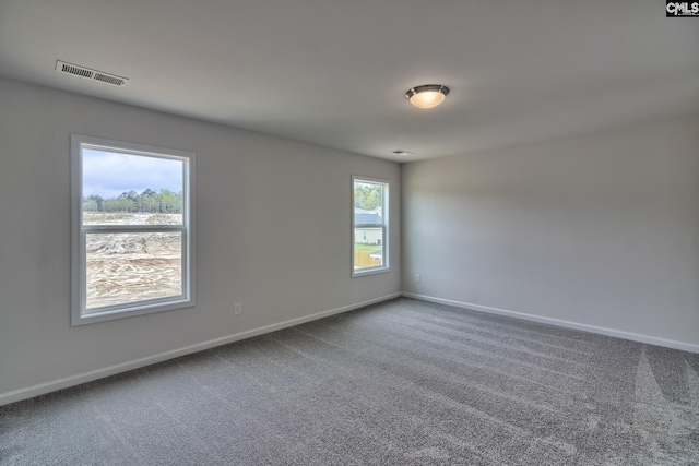 spare room with carpet, visible vents, and baseboards