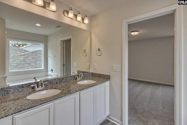 bathroom featuring double vanity, a garden tub, baseboards, and a sink