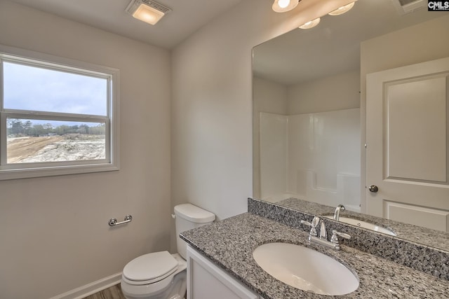 bathroom with toilet, visible vents, vanity, baseboards, and walk in shower