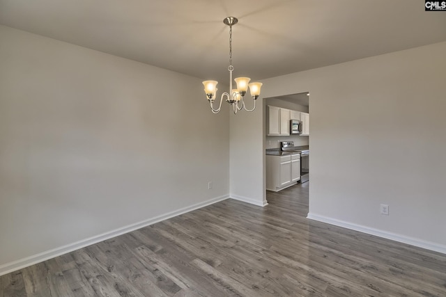 unfurnished dining area with wood finished floors, baseboards, and an inviting chandelier