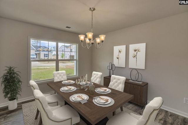 dining space with baseboards, visible vents, a chandelier, and wood finished floors