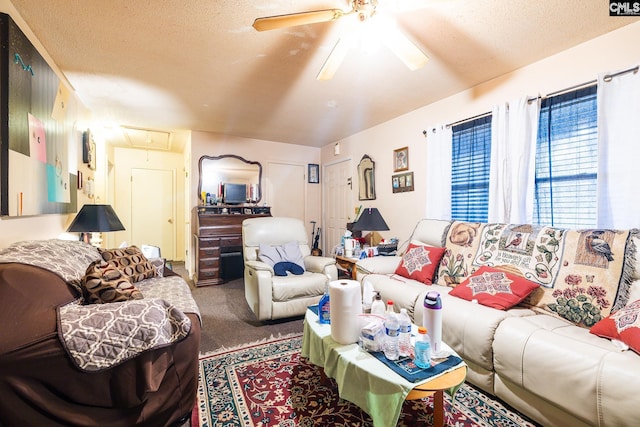 carpeted living room featuring a textured ceiling, attic access, and a ceiling fan