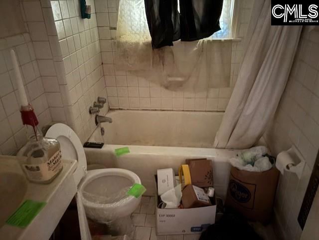 full bath with tile walls, toilet, and shower / bathtub combination with curtain