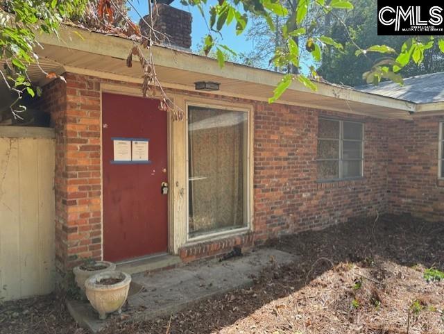 property entrance featuring brick siding and a chimney