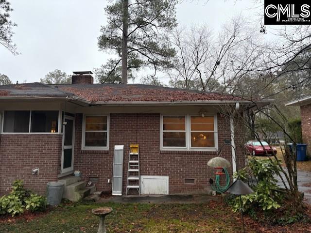 exterior space with entry steps, crawl space, brick siding, and a chimney