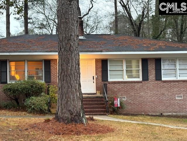 view of front of property with crawl space, brick siding, and a chimney