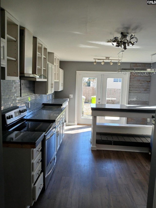 kitchen featuring tasteful backsplash, wall chimney exhaust hood, glass insert cabinets, dark wood-type flooring, and stainless steel range with electric cooktop