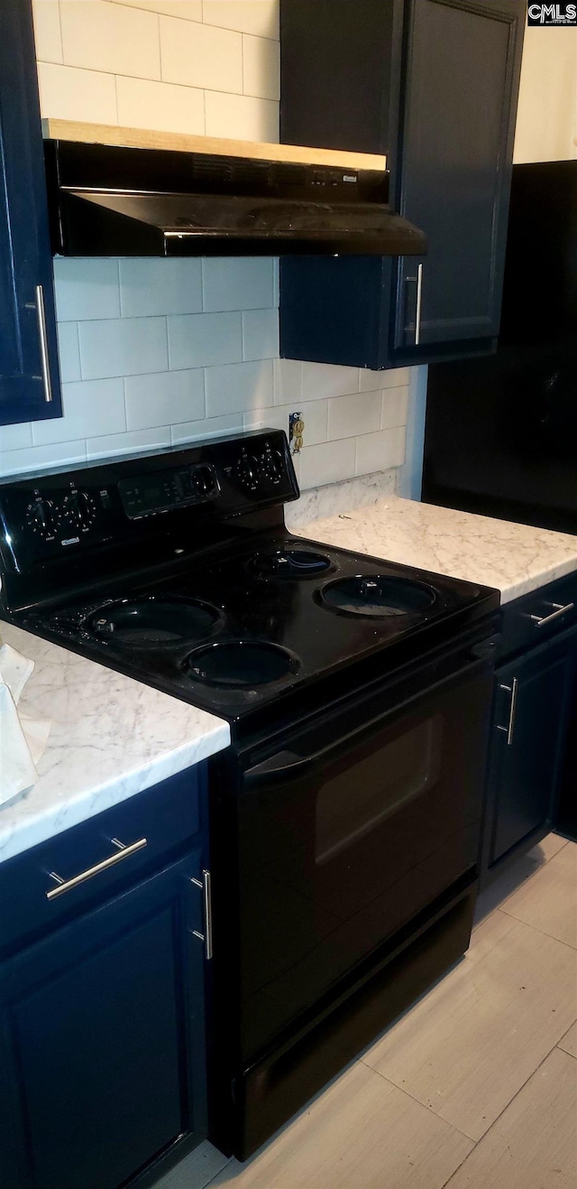 kitchen with under cabinet range hood, light stone countertops, light wood finished floors, black electric range oven, and tasteful backsplash