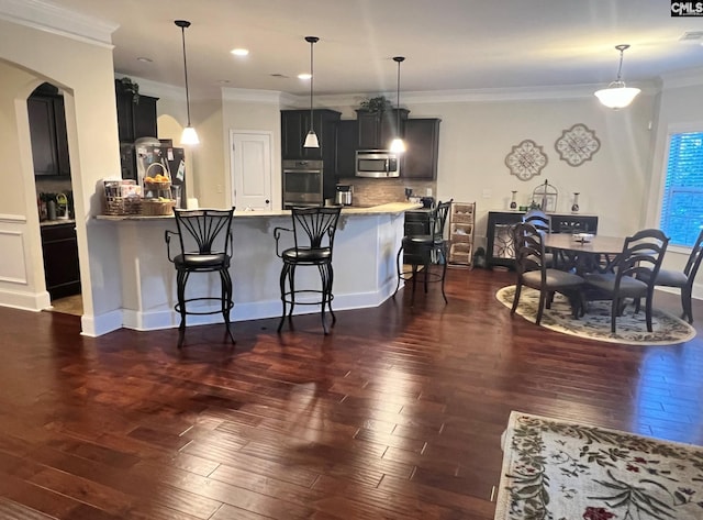 kitchen featuring a peninsula, stainless steel appliances, decorative light fixtures, and a kitchen breakfast bar