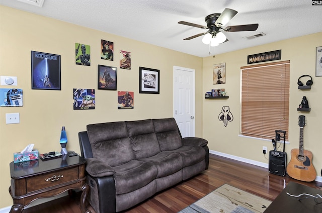 living room with a textured ceiling, visible vents, baseboards, a ceiling fan, and dark wood finished floors