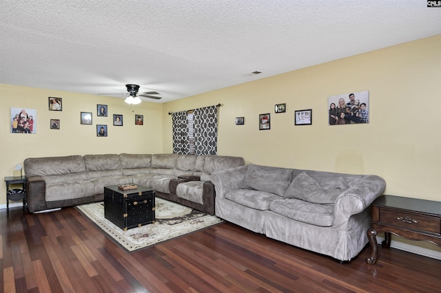 living area with a ceiling fan, visible vents, dark wood finished floors, and a textured ceiling