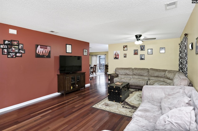 living room featuring dark wood-style flooring, visible vents, and a textured ceiling